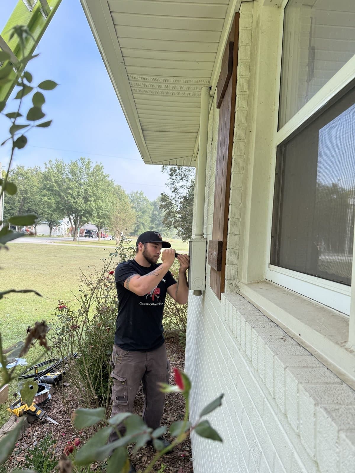 Spark Medic electrician repairing exterior lighting and wiring under the eaves of a Huntsville home