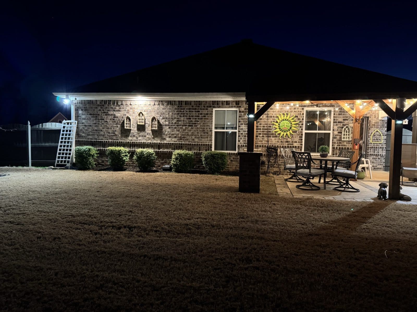 Covered patio and backyard pavilion lit at night by Spark Medic exterior lighting